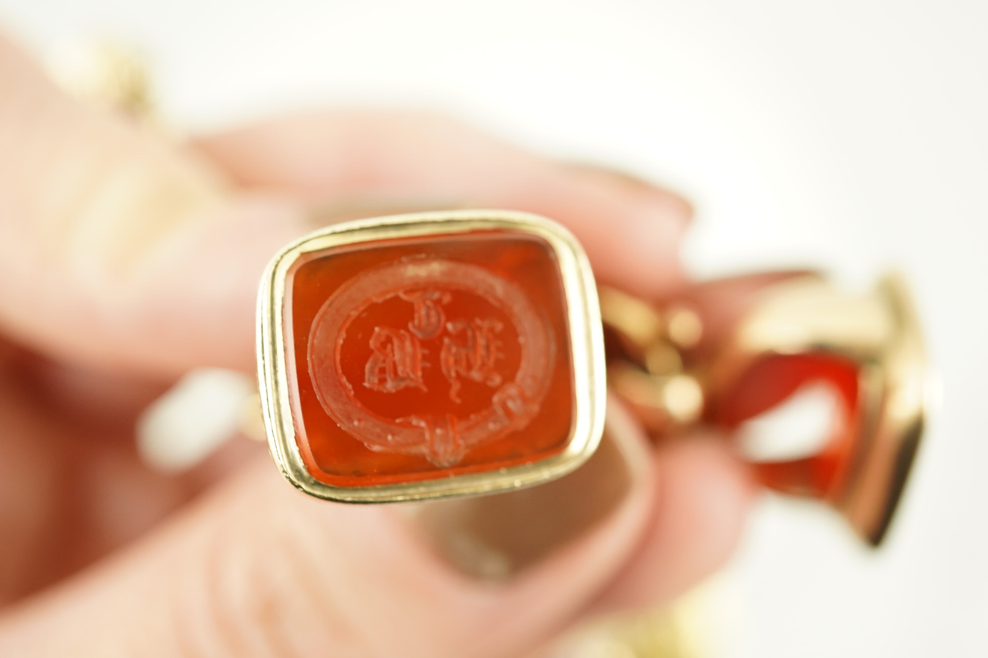 An Edwardian 15ct gold curb link charm bracelet with heart shaped padlock clasp, hung with six assorted gold overlaid and carnelian set fob seals